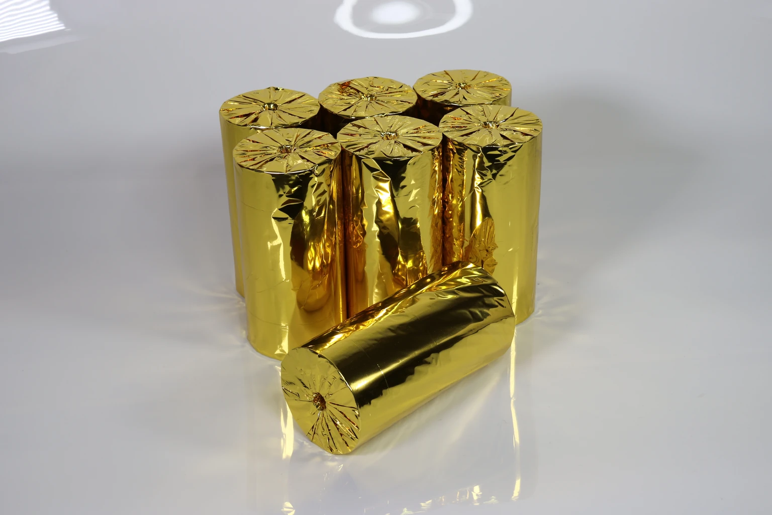 Gold-coloured wrapped paper rolls arranged upright with one roll laid horizontally