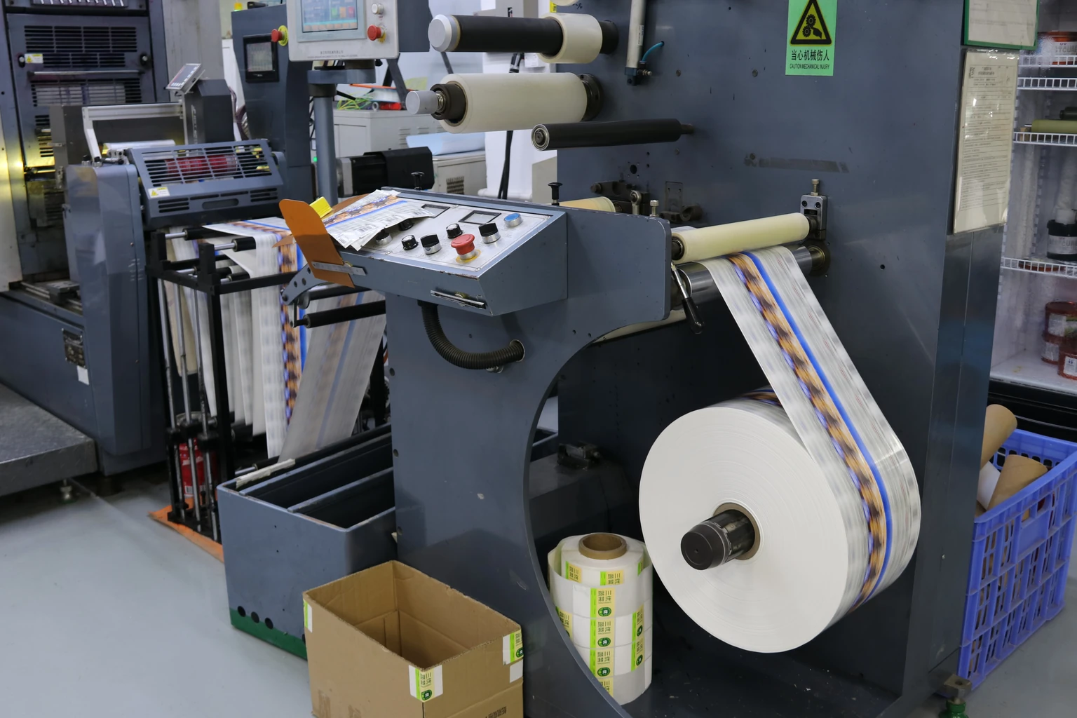 Printed label web passing through rollers beside machine controls