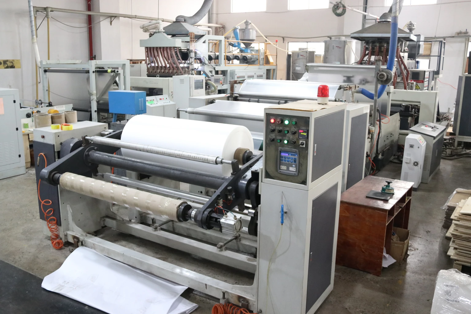 Paper processing equipment with a large white roll and sheets at the outfeed