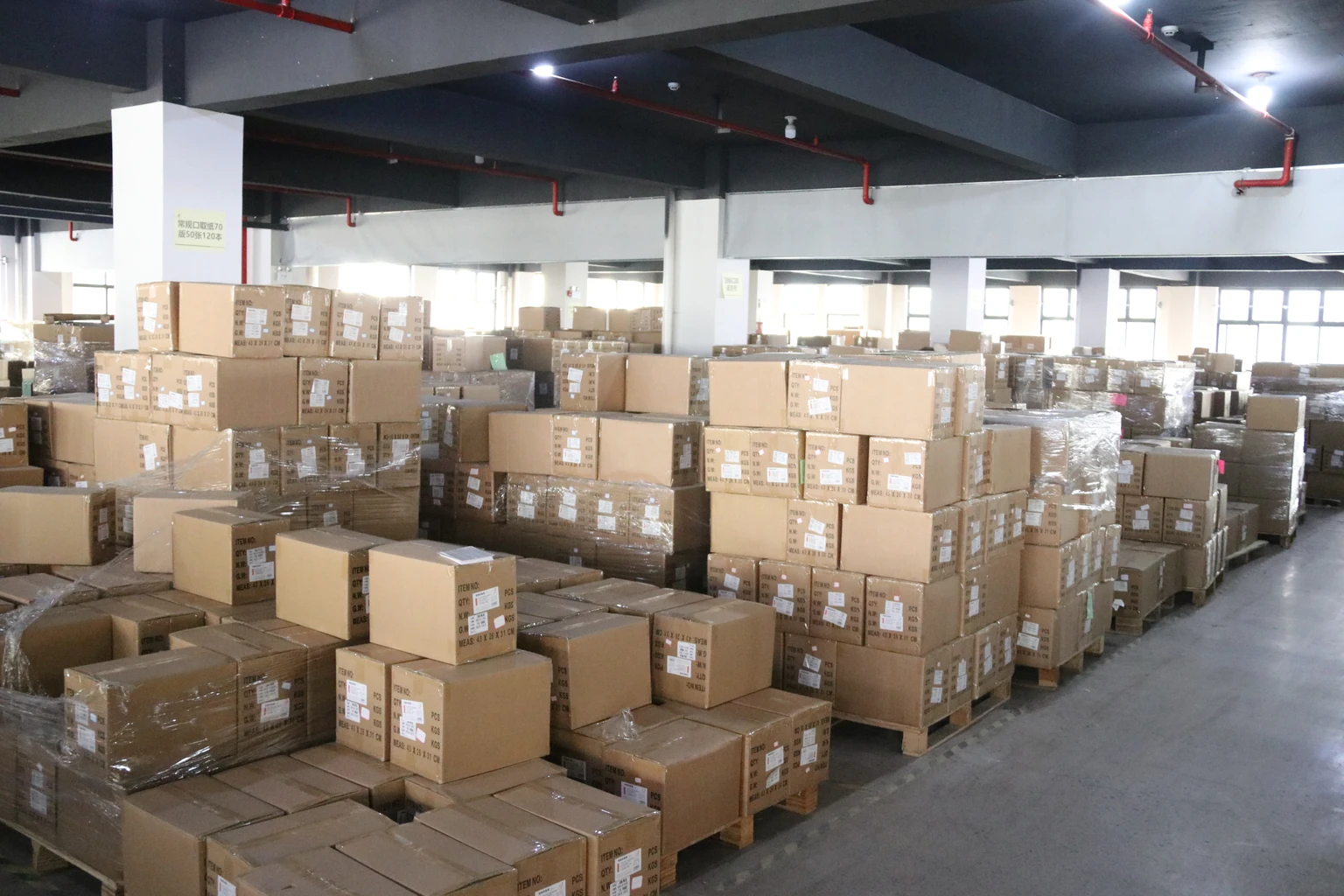 Marked cardboard cartons stacked on pallets inside a warehouse