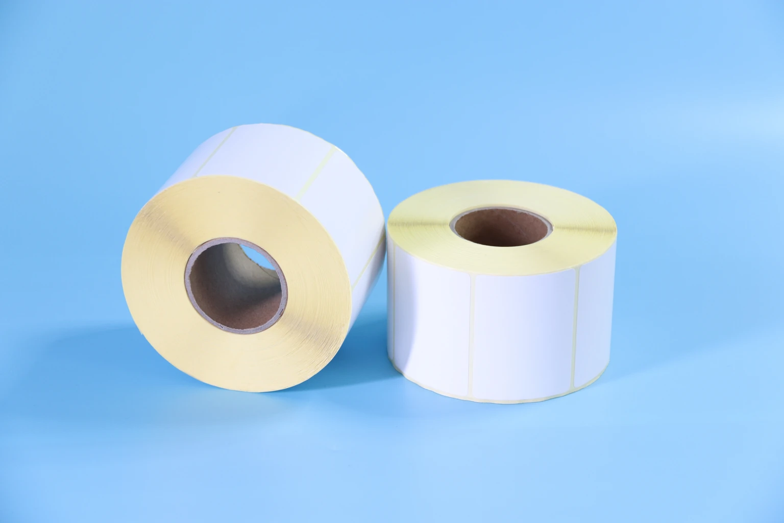 Two white die-cut label rolls with yellow release liner and cardboard cores
