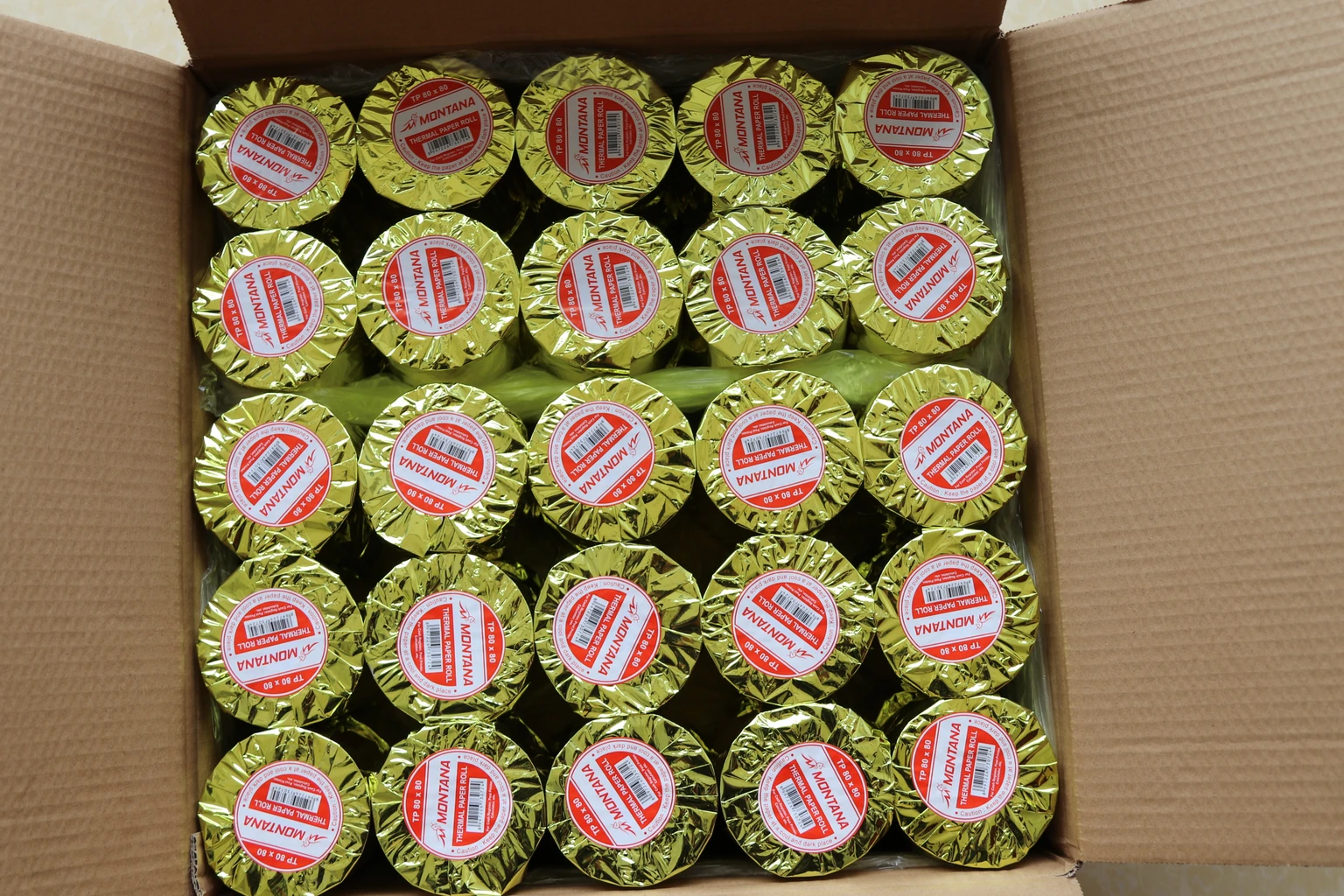 Gold-coloured wrapped rolls with round identification labels inside a carton