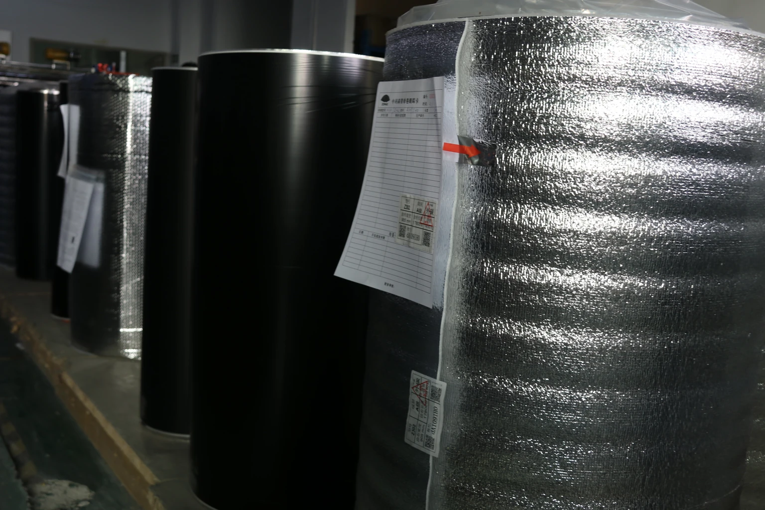 Large black ribbon stock rolls with protective wrapping and identification sheets