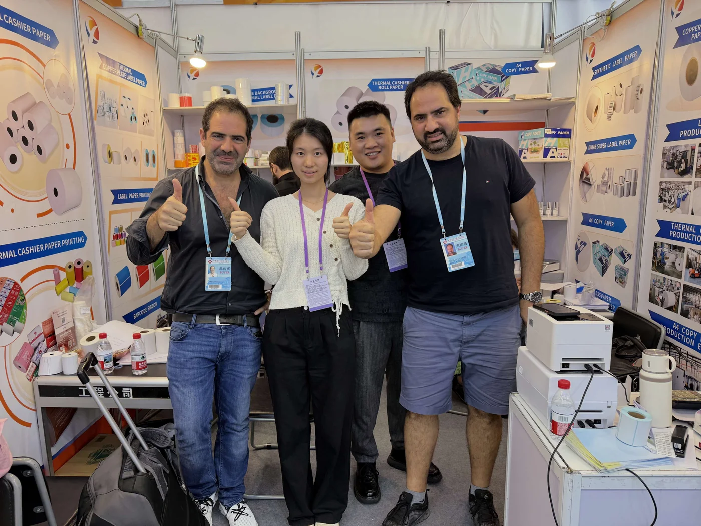 Four people posing beside paper products at the Chenxin exhibition stand